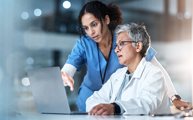 Healthcare professionals collaborating in front of a laptop