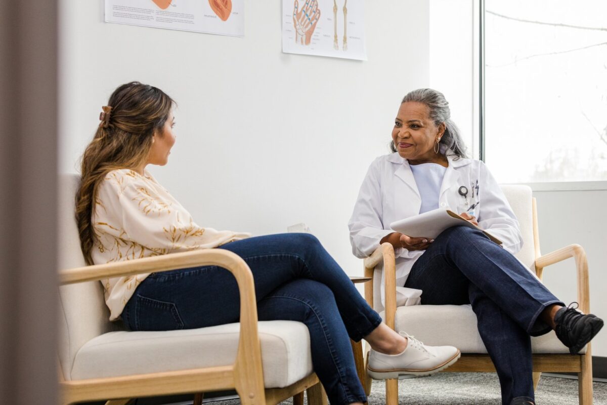 Patient and doctor sit on chairs and talk about the patient's history.