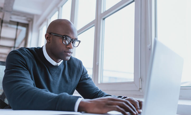 Professional working on a laptop in a bright office space.