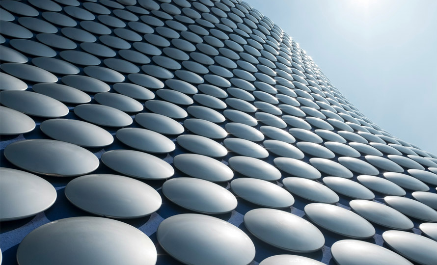 Abstract architectural building facade with repeating circular panels against the sky.