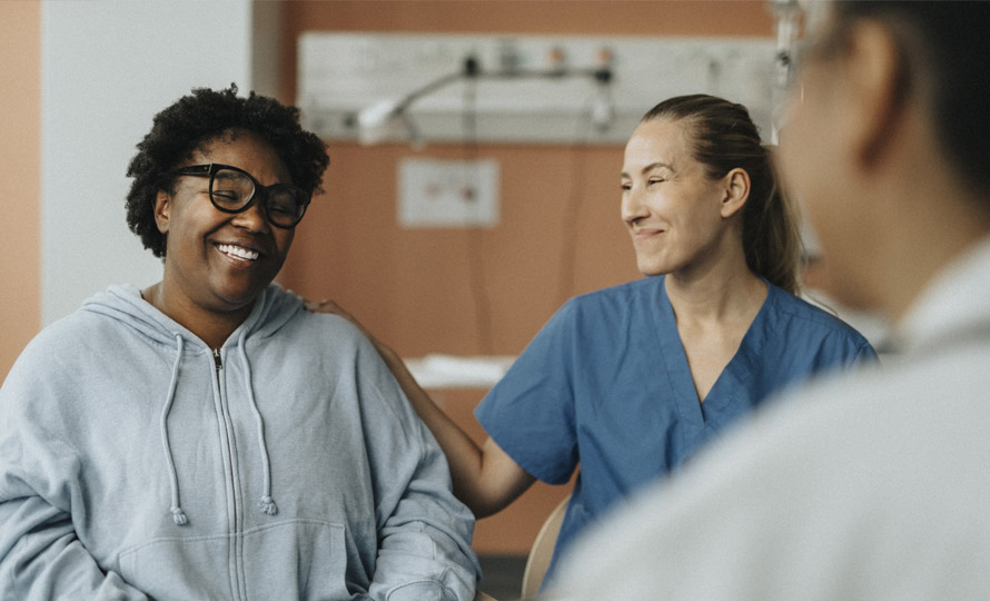 Smiling patient with a supportive nurse in a healthcare setting.