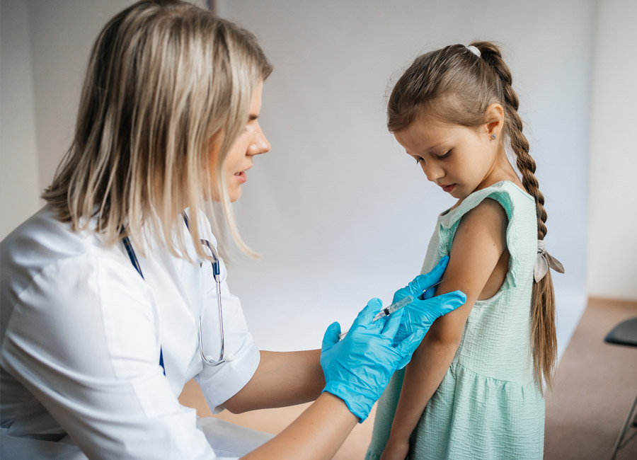 Healthcare professional giving a young girl a vaccination shot.