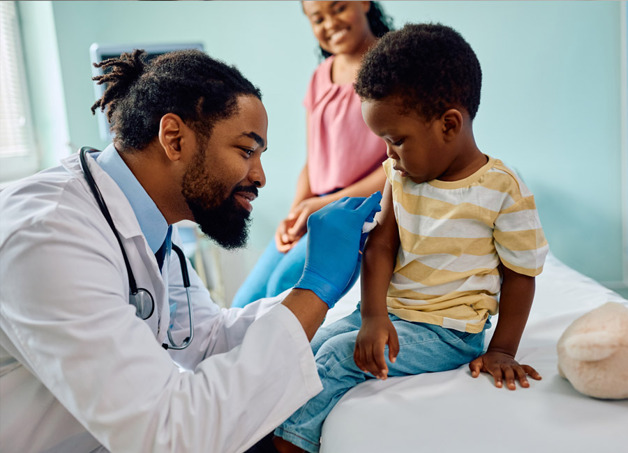 Doctor giving a young boy a vaccination while his mother looks on.