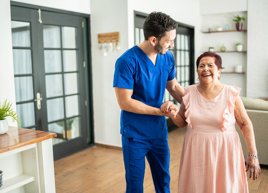 Healthcare professional assisting an elderly woman while walking in a home setting.