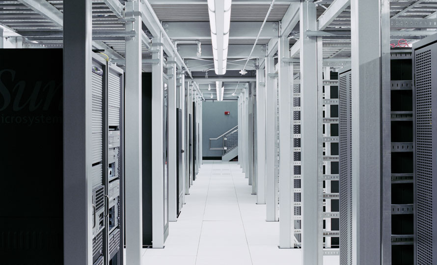 Modern data center with rows of server racks and bright overhead lighting.