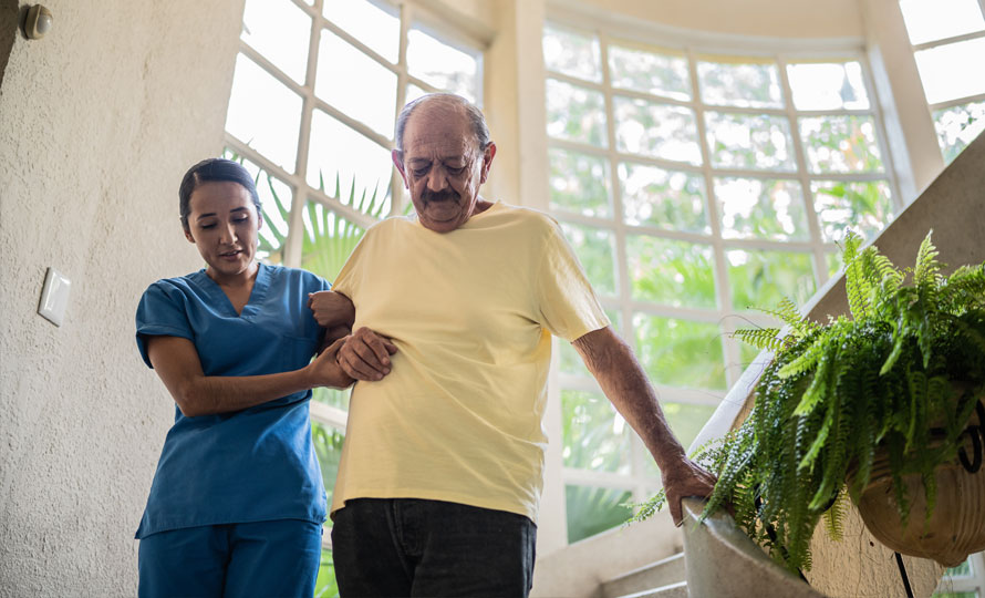 A medical professional helping a patient down stairs.